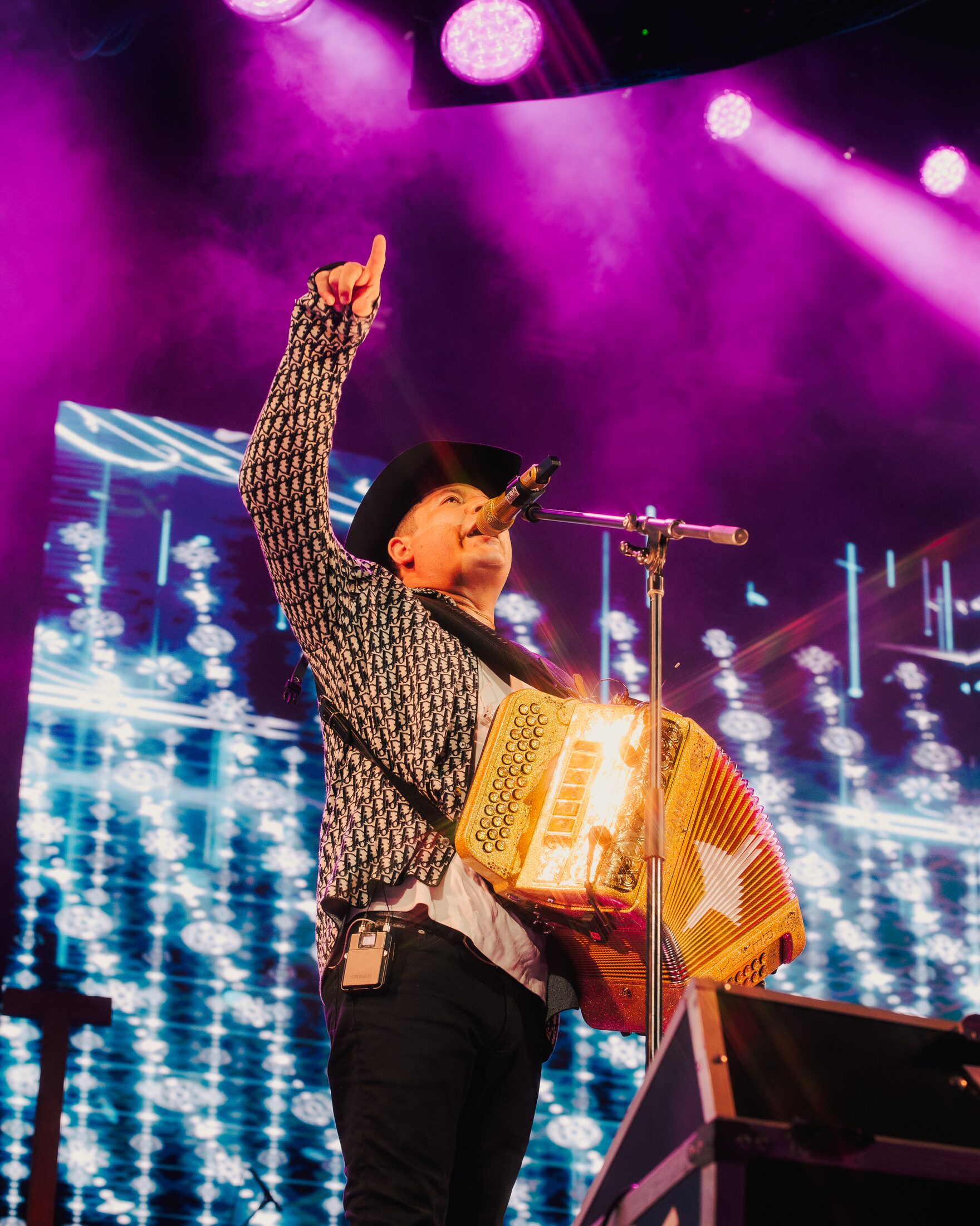 Remmy Valenzuela tocando el acordeón bajo luces magenta
